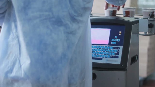 Factory worker check quality of product on automated production line at dairy factory/Food production/Computer controlled conveyor belt/Industrial equipment/Manufacturing equipment