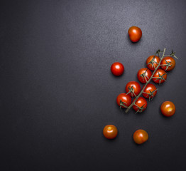 Fresh juicy cherry tomatoes on a branch on the chalkboard border ,place for text on wooden rustic background top view