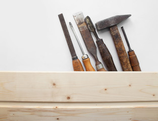 Old-fashined rusty carpenter`s tools lying under wooden tile boards composition.