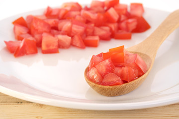 Tomato / Pile of chopped fresh tomato on wooden spoon.