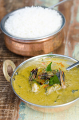 A delicious spicy prawn green curry, served with sticky rice in a rustic metal pan.