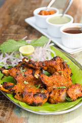 Delicious tandoori chicken starter, served with lime, onion, mint, yoghurt and sauces, on a banana leaf base.