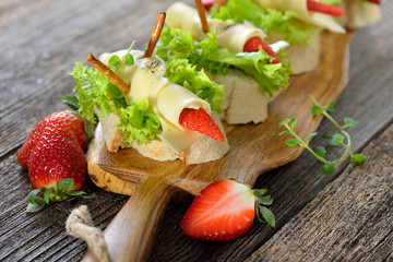 Käseröllchen mit Erdbeeren auf Ciabattabrot mit Salatblatt - Cheese rolls with strawberries on Italian ciabatta bread with lettuce leaves