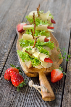 Käseröllchen mit Erdbeeren auf Ciabattabrot mit Salatblatt - Cheese rolls with strawberries on Italian ciabatta bread with lettuce leaves