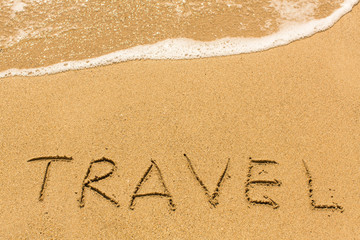 Travel - written manually on the texture of sea sand, with the wave.