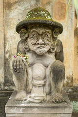 Traditional demon guard statue carved in stone on Bali island.