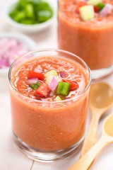 Traditional Spanish cold vegetable soup Gazpacho made of tomato, cucumber, bell pepper, onion, garlic and olive oil (Selective Focus, Focus on the front of vegetables on top of the soup)