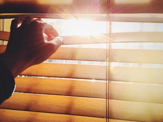 Warm midday sun behind window blind.