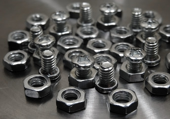 Screw bolts and hex nuts on metal surface macro shot