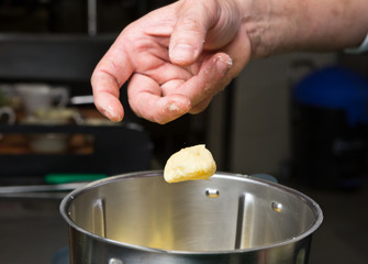 Close up shot of a hand dropping butter onto fluffy peeled potatoes in a blender.