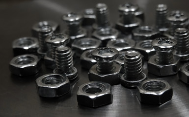 Screw bolts and hex nuts on aluminium surface closeup shot