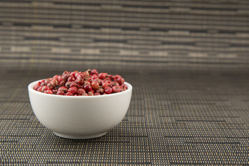 Peppercorns mixed in bowl on dark background. Top view with copy space.