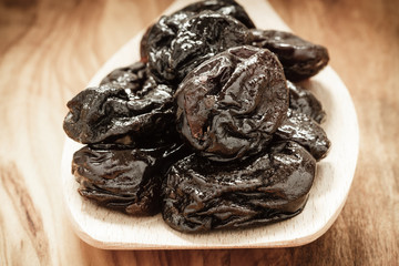 dried plums prunes on wooden spoon