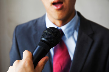 Young talking man holding microphone without confidence on isolated white background