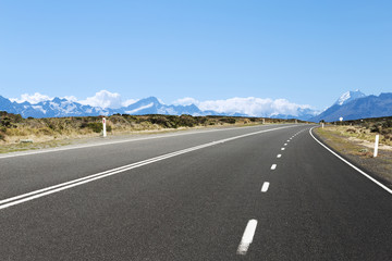 empty asphalt road near snow mountains in new zealand
