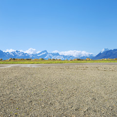 empty rural road near snow mountains in fine day in new zealand