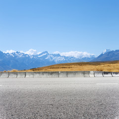 empty concrete road near snow mountains in new zealand