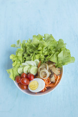 Healthy salad bowl on blue background, vertical style