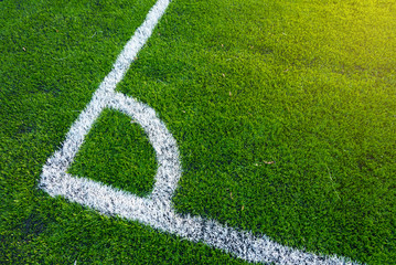 Top down angle view of white line on a green soccer field.