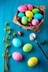 Painting Easter eggs in bright colors on the wooden table