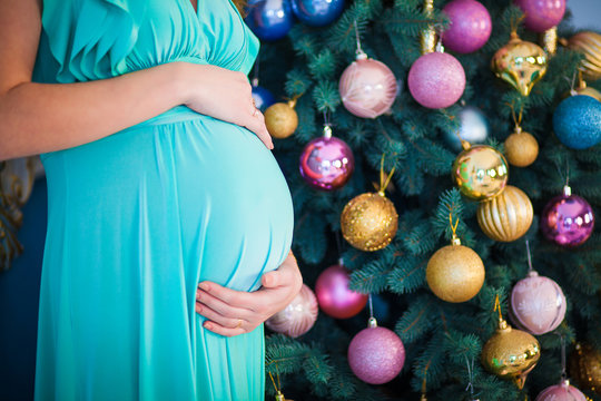 pregnant woman near Christmas tree. belly closeup