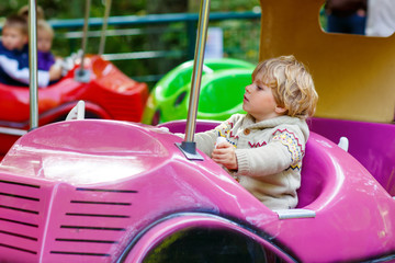 Fototapeta na wymiar Little kid boy on carousel in amusement park