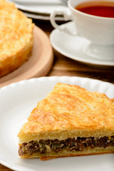Piece of pie with minced meat on wooden table.