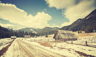 Fototapeta na wymiar Vintage toned wooden huts by a road in Tatra Mountains, end of winter and beginning of spring, Poland.