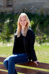 Obraz premium Cool blonde girl sitting on a wooden bench