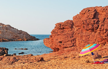 Minorca, isole Baleari, Spagna: sabbia rossa e un ombrellone sul sentiero per Cala Pregonda, la...