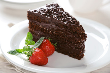 Chocolate cake with chocolate cream and fresh berries on plate, on light background