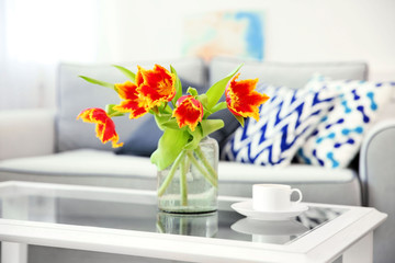 A bouquet of red tulips in a glass on white table.