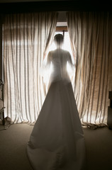 Toned shot of elegant bride looking out window at hotel