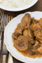 boiled chicken with beer sauce in white plate and rice in bowl on brown background
