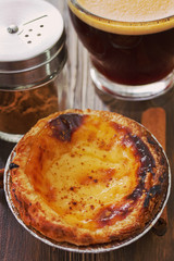 portuguese dessert pastel de nata on white dish and cup of coffee on brown wooden background