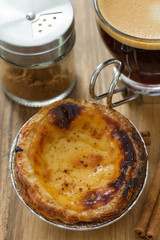portuguese dessert pastel de nata on white dish and cup of coffee on brown background