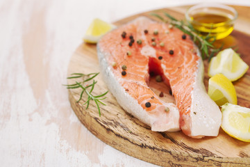 fresh salmon with lemon and rosemary on wooden board on white background