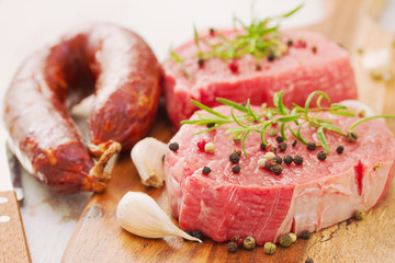 raw meat with smoked sausage, pepper and garlic on wooden board