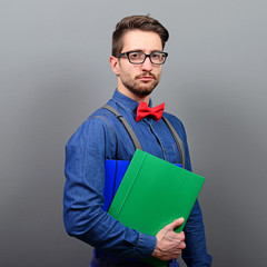 Handsome young businessman holding notes against gray background