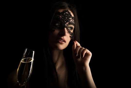 elegant woman in lace mask toasting champagne glass
