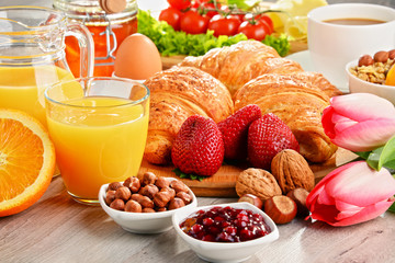 Breakfast consisting of croissants, coffee, fruits, orange juice