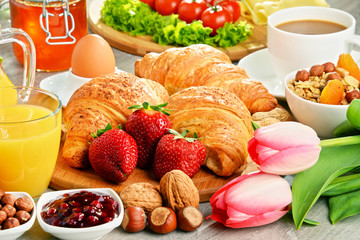 Breakfast consisting of croissants, coffee, fruits, orange juice