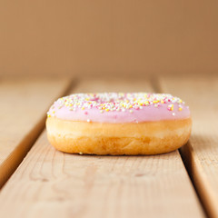 en munk med rosa glasyr och strössel