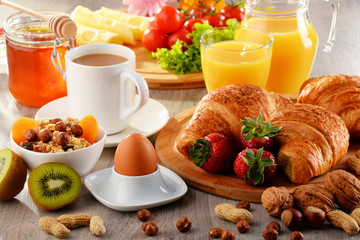 Breakfast consisting of croissants, coffee, fruits, orange juice