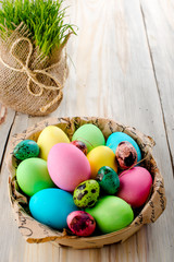 Colorful Easter eggs in the basket on wooden background