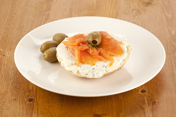 a plate of slice bagel with salmon and olives