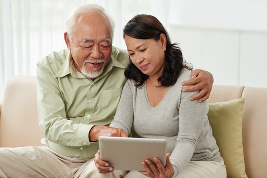 Aged Vietnamese Man Showing His Wife How To Use Tablet Computer