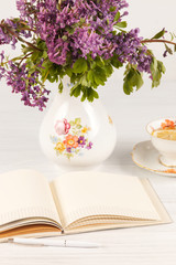 Tea with  lemon and bouquet of  lilac primroses on the table