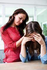 Unhappy young woman with friend at home