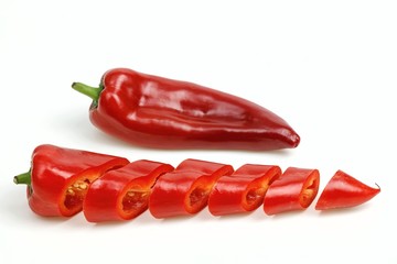 Pointy red pepper and one cut into pieces, on white background.